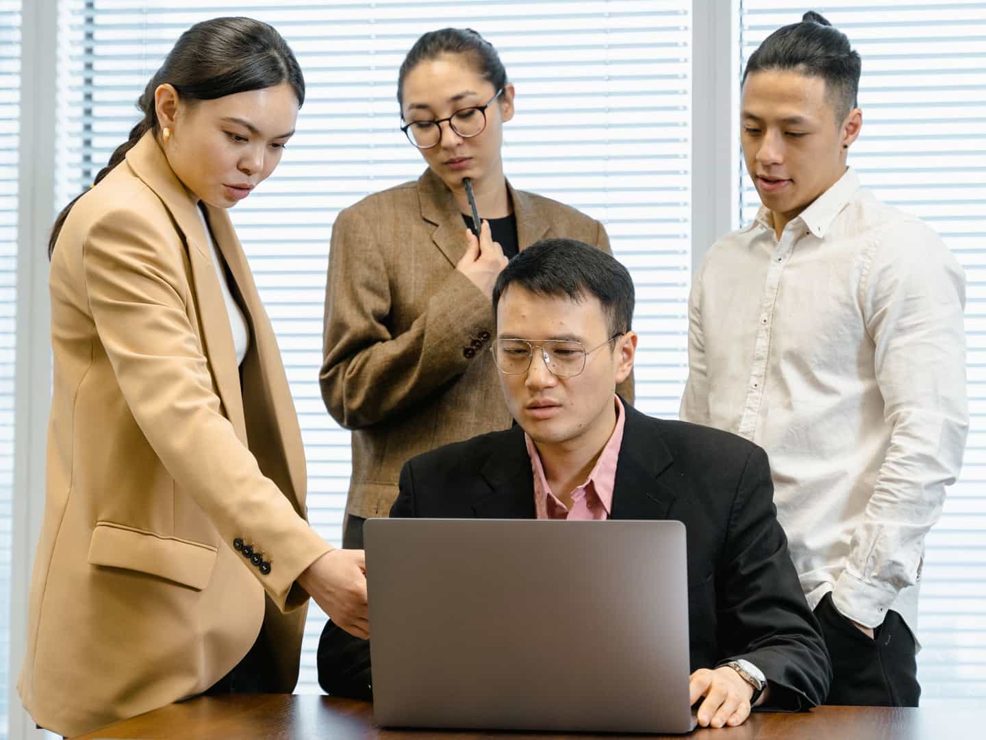 A team gathered around a laptop reviewing work together